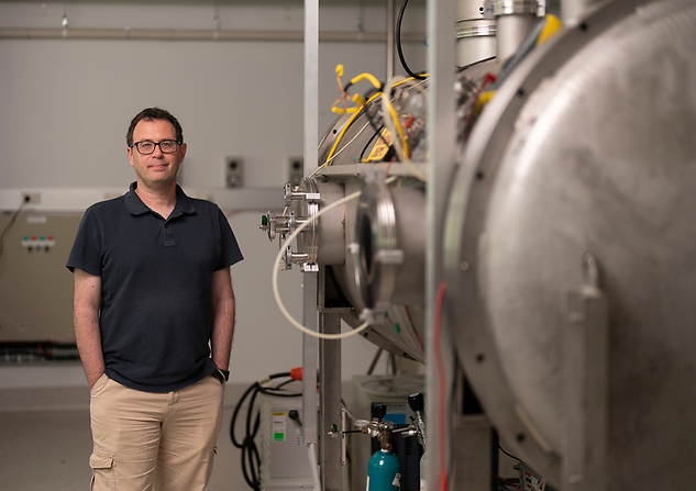 Dimitris standing next to the Wombat space simulation chamber at the Research School of Physics, ANU